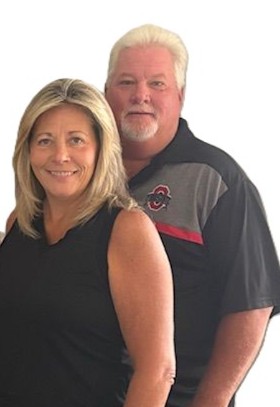 Smiling couple posing against white background.